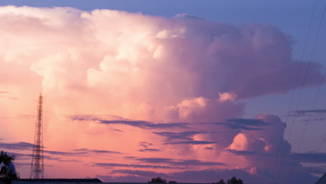 burbujeante naranja cumulonimbus nube de tormenta lapso de tiempo en el sol de la tarde poniente con torre de mástil de telecomunicaciones silueta y hombre en el teléfono sobre los tejados de la ciudad, sudeste de asia