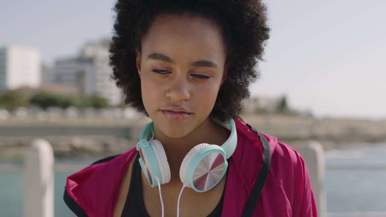 retrato de una atractiva mujer afroamericana en ropa deportiva posando con confianza en una playa soleada