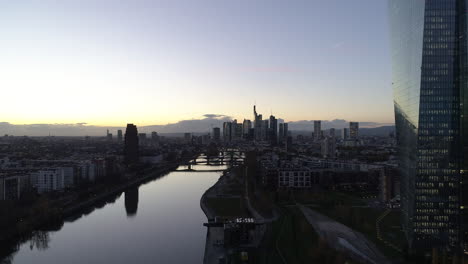 AERIAL:-Establishing-Shot-of-Frankfurt-am-Main,-Germany-Skyline-at-Dusk-Sunset-light-with-European-Central-Bank-and-Downtown-City-Lights