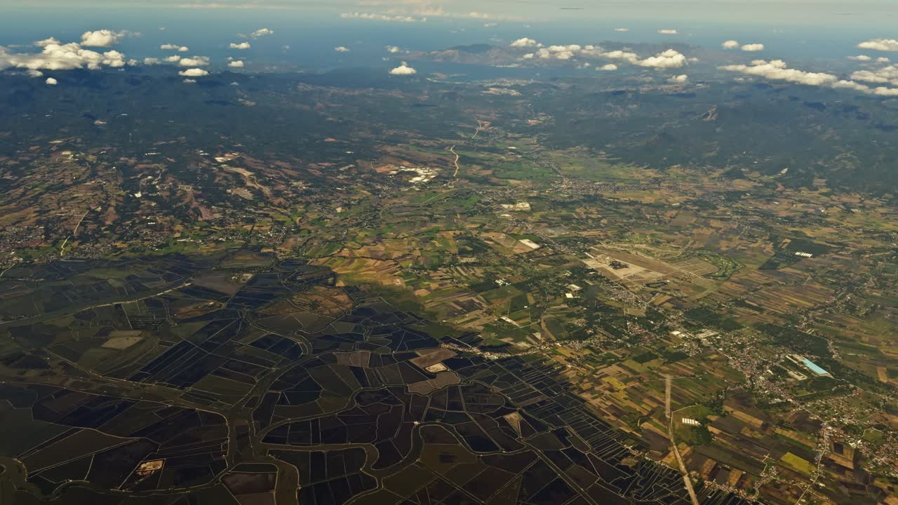 Veduta aerea delle Filippine da un finestrino dell'aereo, che rivela paesaggi mozzafiato, coste, nuvole e la bellezza naturale delle isole tropicali sottostanti.