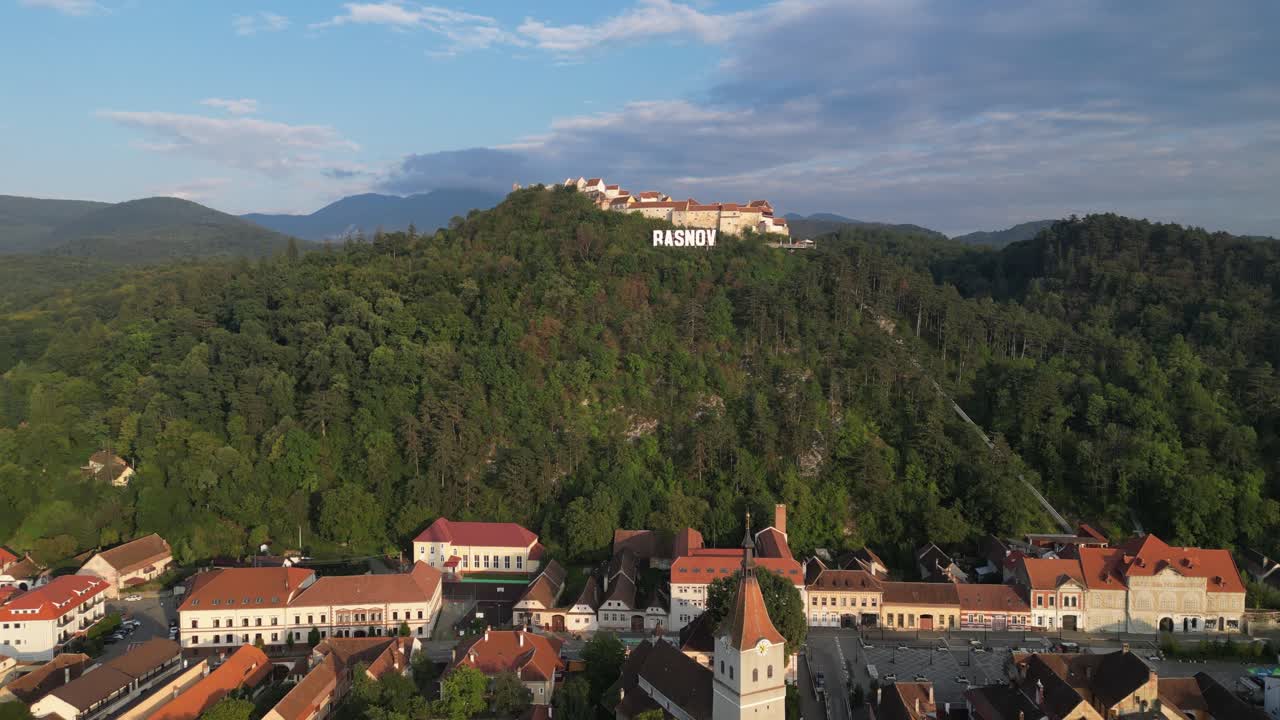 Rasnov by og festningsslott på toppen av en ås i Karpatene, Romania - Luftfoto 4k Pedestal