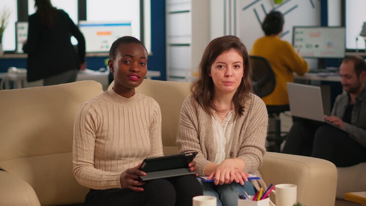 Team from start up company talking during video meeting sitting on couch