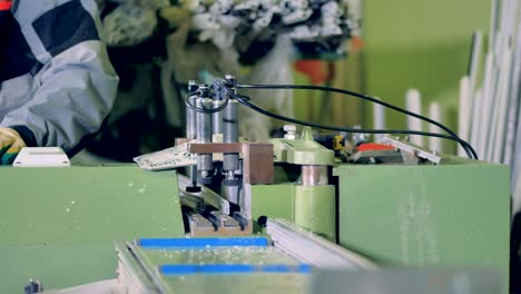 a worker operates a rotary saw for small plastic profiles.