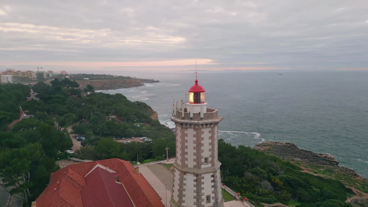 Lighthouse beam shining shore under gloomy sky for maritime navigation aerial