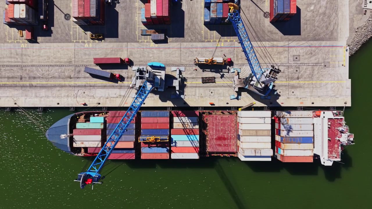 Cargo ship loading containers at a busy port in sunlight