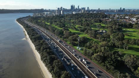 Slow-backwards-flight-showing-busy-intersection-beside-Golf-Club-in-Perth-City,-Western-Australia