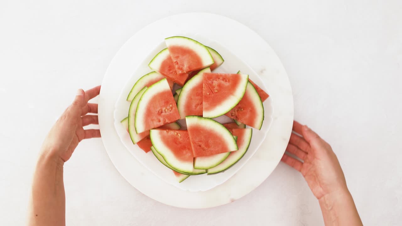 persona sosteniendo un cuenco de sandía cortada, video en primer plano, fondo blanco, plano
