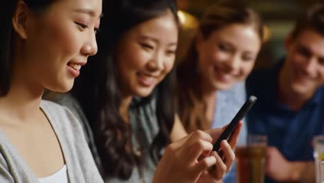 engaged group of friends enjoying time together while one person uses a smartphone to share moments and connect digitally in a lively atmosphere