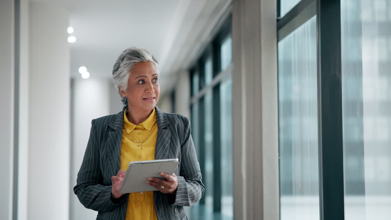 Businesswoman using tablet in modern office hallway