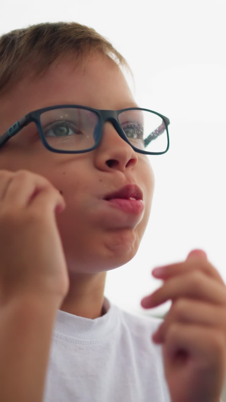 se ve a un niño sosteniendo un rollo de salchichas, observándolo cuidadosamente antes de ponerlo en su boca, mira hacia la derecha con una sonrisa mientras disfruta de su bocadillo