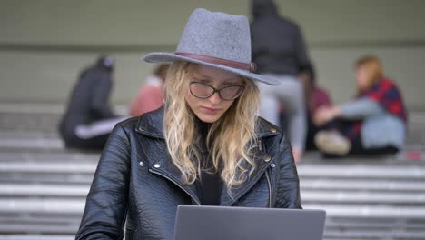 Junge-Schöne-Frau-Mit-Blonden-Haaren,-Die-Draußen-Mit-Ihrem-Laptop-Arbeitet