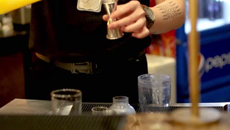 bartender measuring and pouring ingredients for cocktail