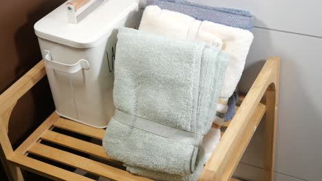 folded towels and laundry bin on wooden shelf