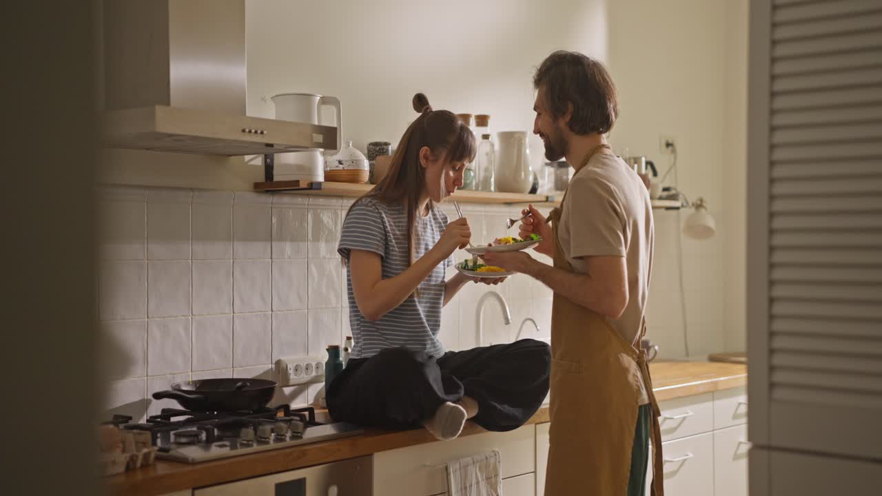 Couple Eating and Cooking in Kitchen