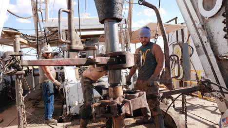 mid-aged strong men work at the oil drilling site. worker arrange the equipment for natural resources production.
