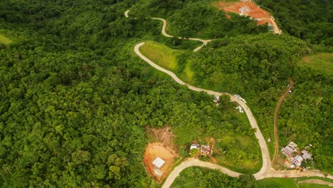 overhead drone shot of winding roads along lush tropical mountains and jungles during daytime at buenavista, catanduanes, philippines