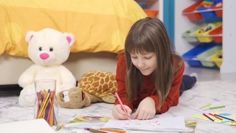 Creative-and-dreamy-little-girl-draws-with-colored-crayons-in-her-room.