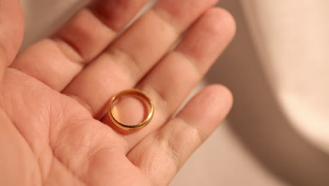 close up of an individual opening her hand and showing a golden wedding band in between her fingers