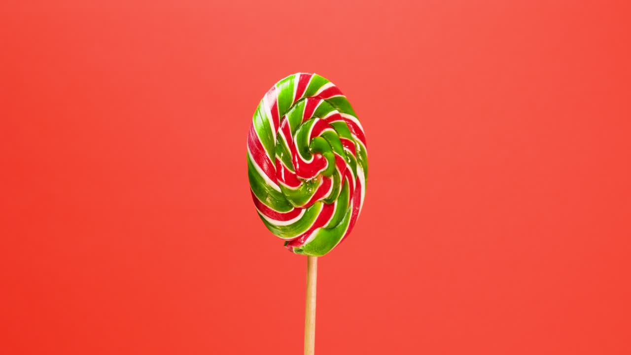 Lecca-lecca a spirale su sfondo rosso. La caramella color caramello sta girando.