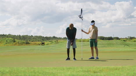 African-american-man-and-caucasian-woman-practicing-golf-on-the-golf-course.