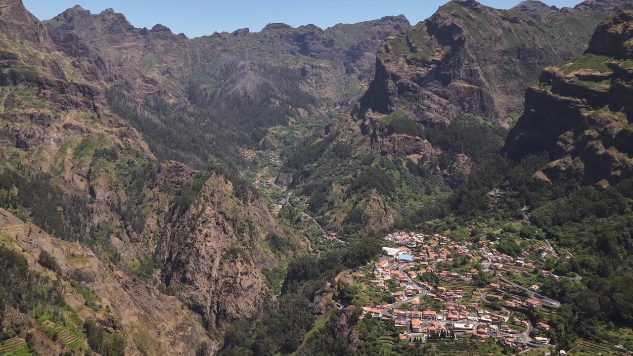 Ripresa con drone di Curral das Freiras immersa in spettacolari valli montane, vegetazione rigogliosa, scogliere rocciose e terreno soleggiato, che mette in risalto i paesaggi naturali mozzafiato della zona
