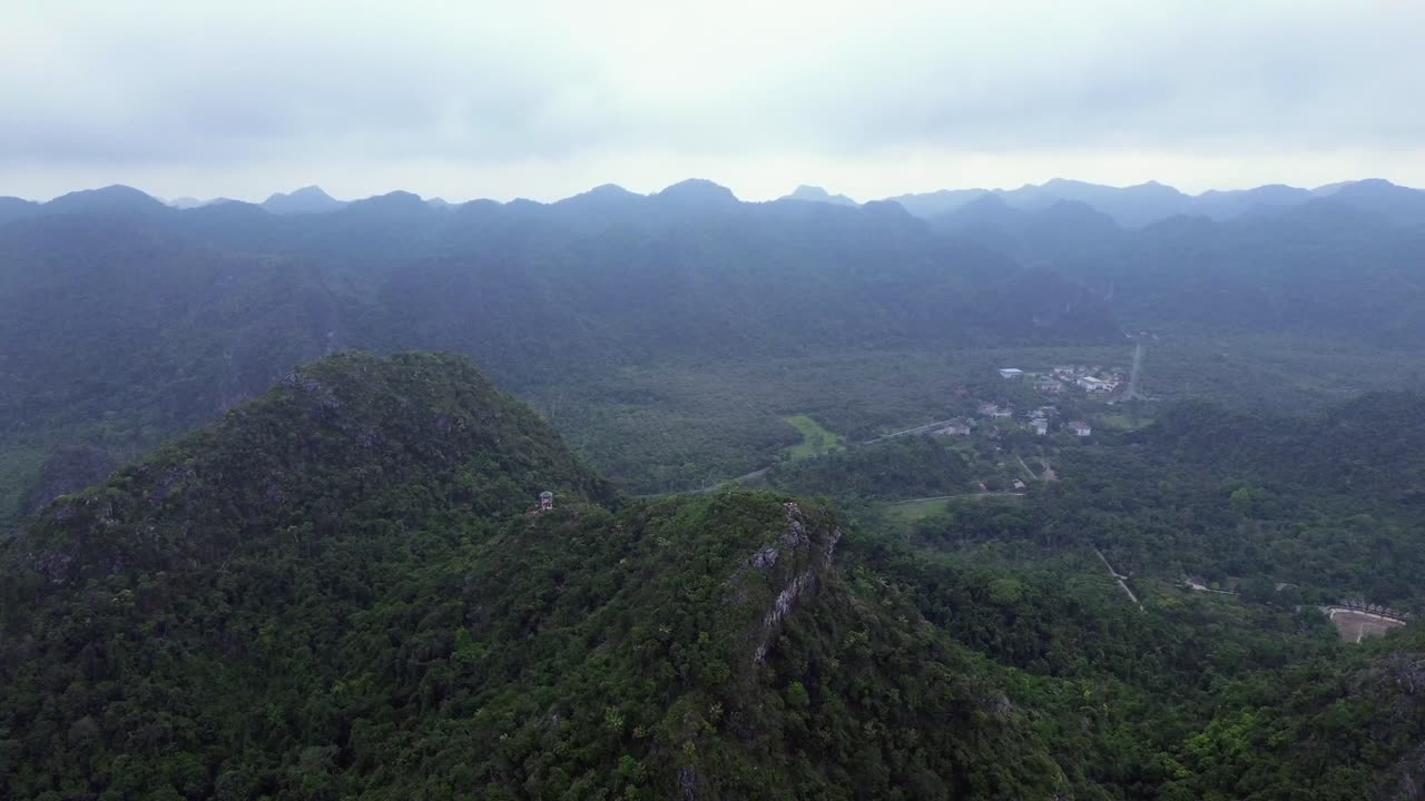Pan right movement along coastal area with tropical forest and rocky peaks