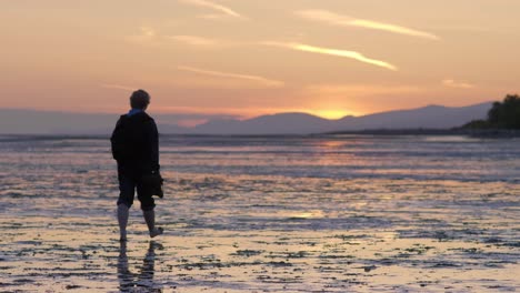 Silhouettierte-Person-Geht-In-Zeitlupe-Am-Strand-Bei-Ebbe-Bei-Sonnenuntergang