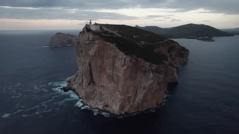 cabo caccia, cerdeña: vista aérea en órbita del faro de este famoso cabo y las olas que rodan sobre la base