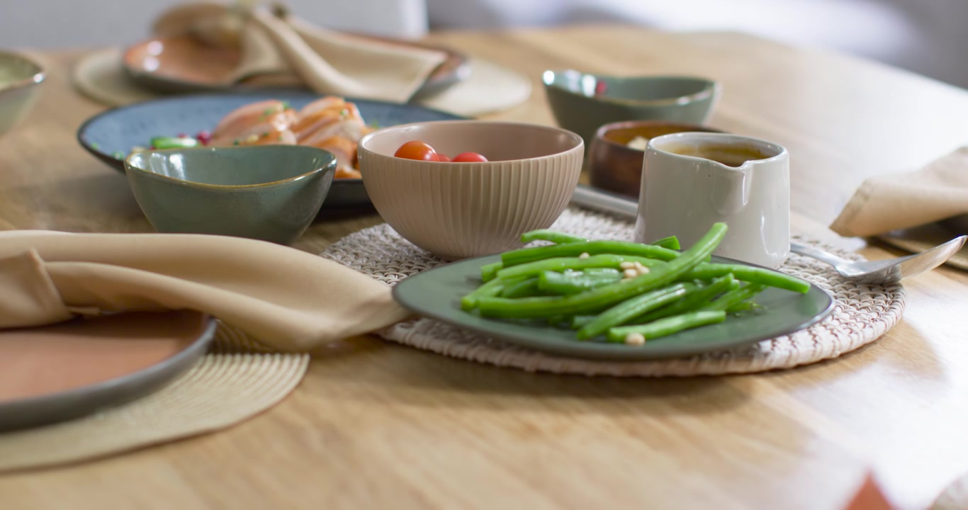 Camera is closing in and focusing on green beans at dining table, highlighting texture and garnish