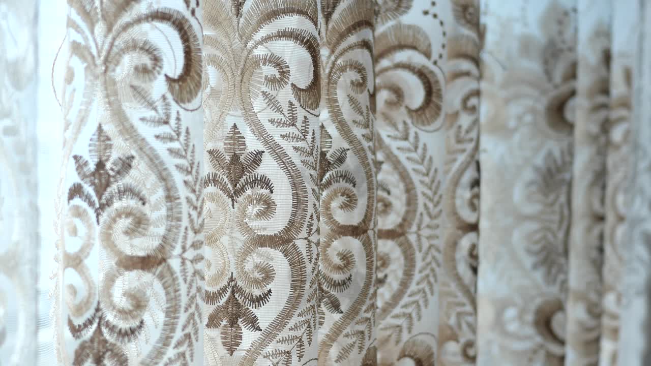 primer plano de cortinas blancas con bordados marrones