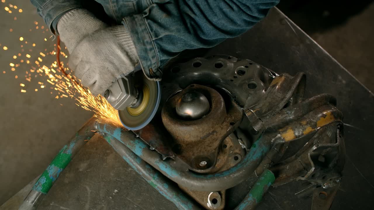 cerrajero lija el metal decorativo inacabado escultura de pez steampunk por molinillo eléctrico con muchas chispas en cámara lenta, metalurgia en taller, 4k 60p prores hq