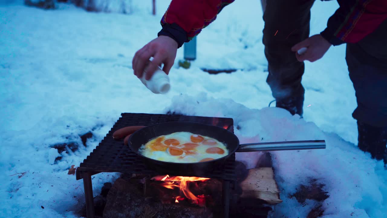 vista recortada de un hombre cocinando huevos sobre leña