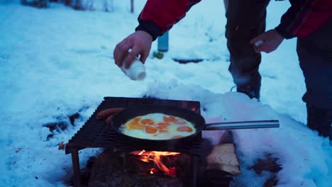 cropped view of a man cooking eggs over firewood