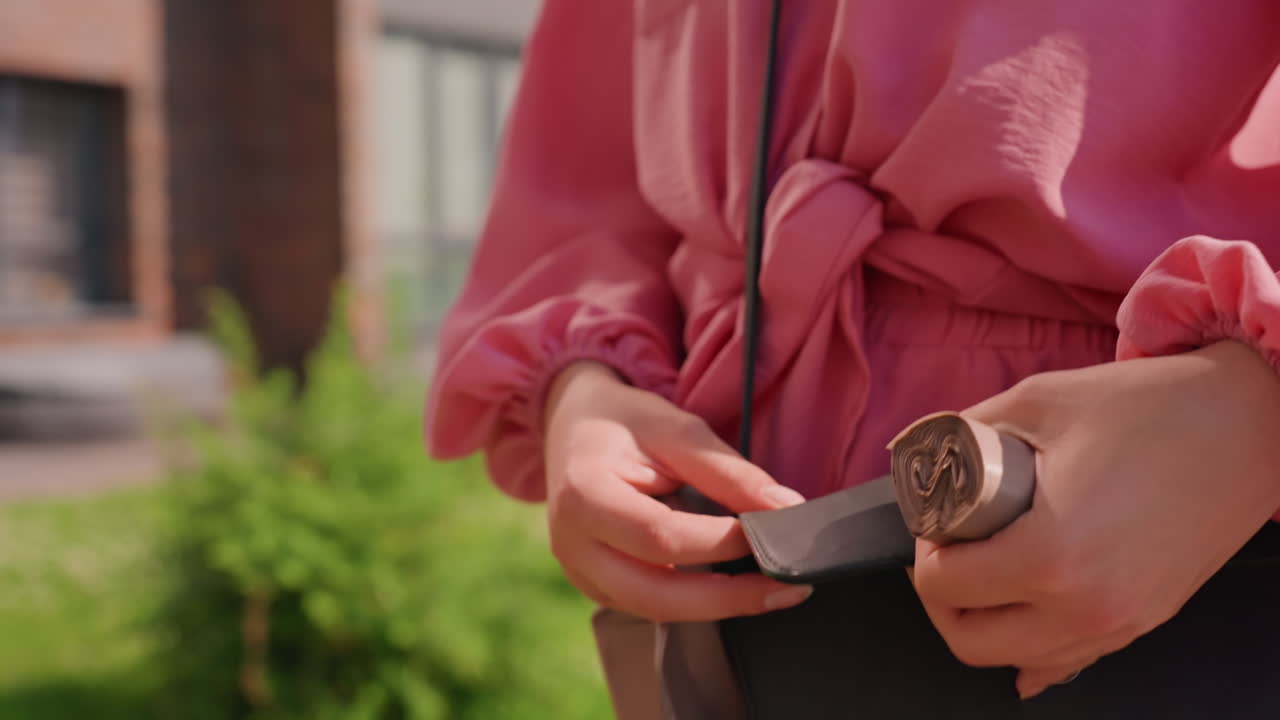 Lady Extracting Coins Outside, Female Retrieves Wallet In Sunlight, Woman Taking Out Coins From Black Leather Purse, Casual Woman In Pink Blouse Reaches Into Leather Purse Outdoors During Walk