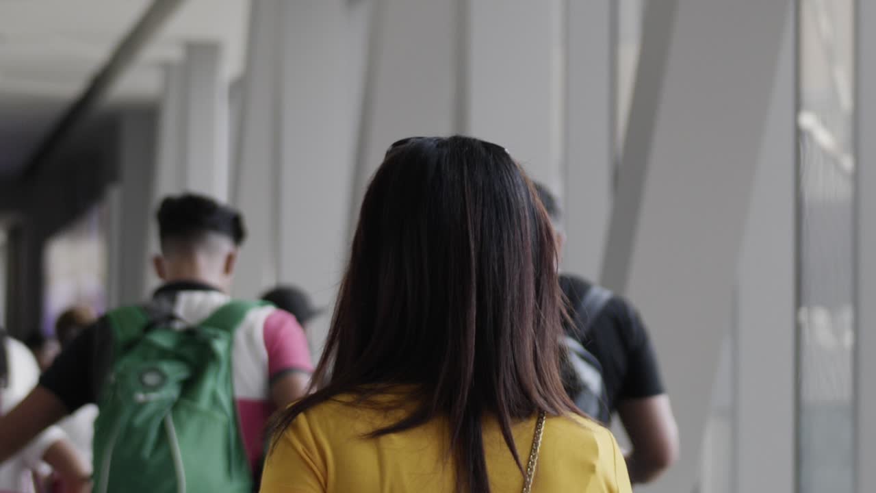 검은 머리에 노란색 셔츠를 입은 젊은 아시아 여성이 uae 두바이에서 슬로우 모션으로 걷는다