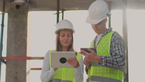 supervisor de un edificio en construcción hombre discutiendo con ingeniero diseñador mujer el progreso de la construcción y examina un plan de construcción.
