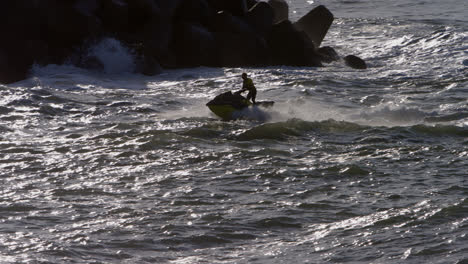 jet ski heads into harbor at sunset in the town of nazare, portugal