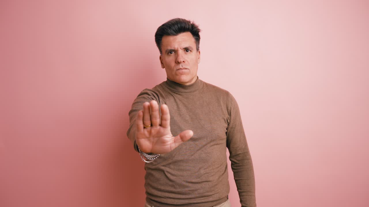 Serious Man Making Stop Gesture Against Pink Background