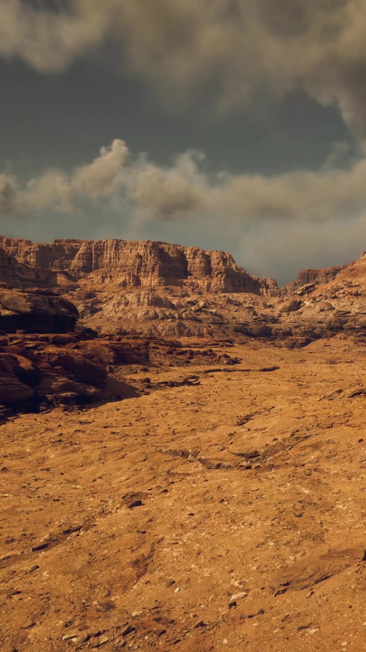 Vista di un paesaggio desertico roccioso con montagne e cielo nuvoloso.