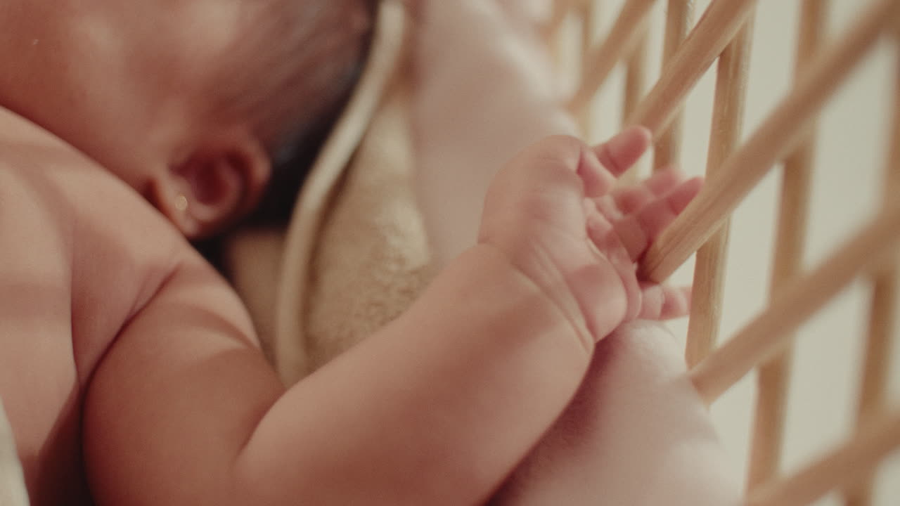 Close up of baby newborn little cute hand playing with the wooden cradle . Natural soft light
