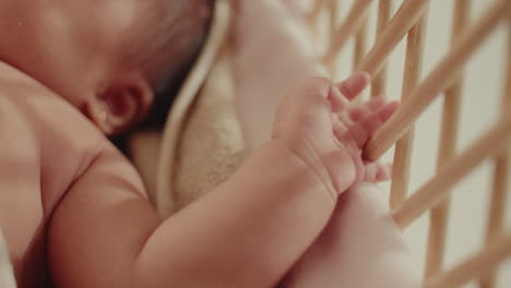 close up of baby newborn little cute hand playing with the wooden cradle . natural soft light