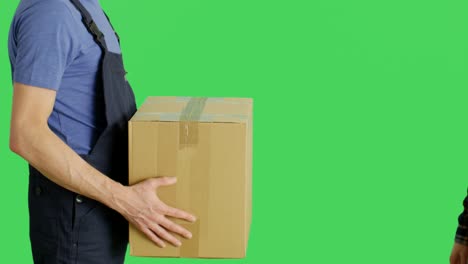 profile mid shot of a loader delivering cardboard box to owner. shot with green screen background.