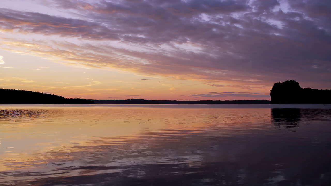 Vibrant Sunset Over a Calm Lake with Silhouetted Shore
