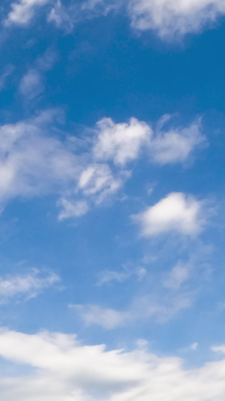 Beautiful little white clouds fly in the sky and disperse in the wind. Low angle view. Timelapse. Vertical video