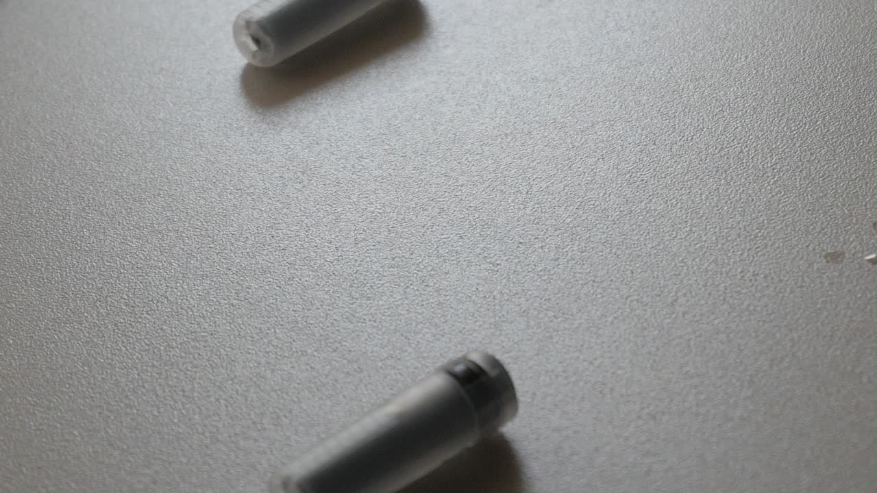 Panning shot of syringes and containers on a white surface