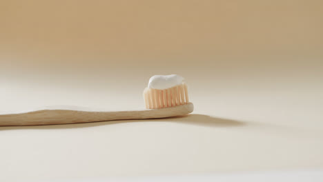 close up of toothbrush with toothpaste on beige background