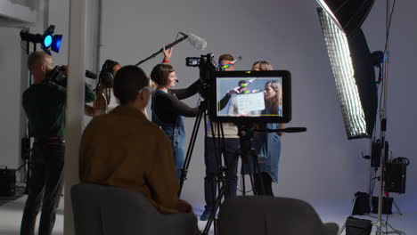 female production assistant uses clapperboard as actors shoot movie or video in studio with film crew and director