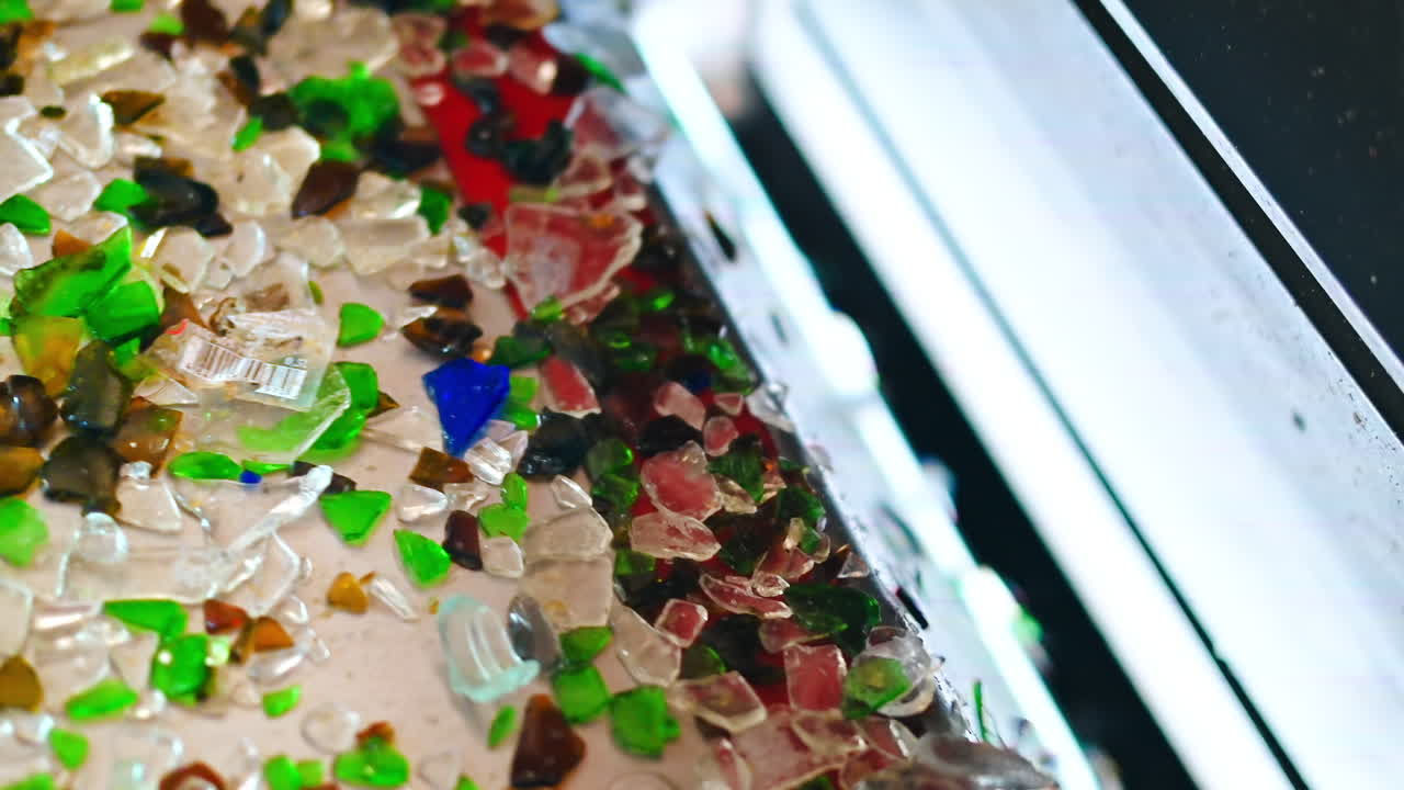 Process of sorting glass garbage on a vibrating conveyor belt at waste sorting plant. Slow motion