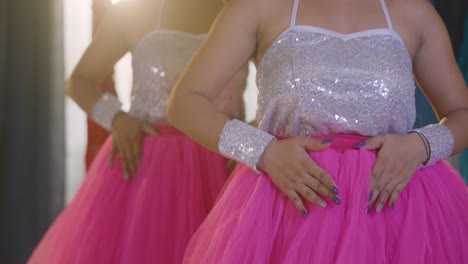 Two-Indian-girls-dancing,-wearing-matching-pink-Barbie-dresses,-medium-shot-without-face,-below-shoulder