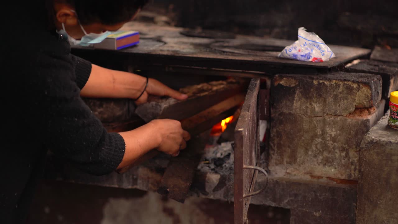 mujer encendiendo estufa de leña. mujer en cocina rural